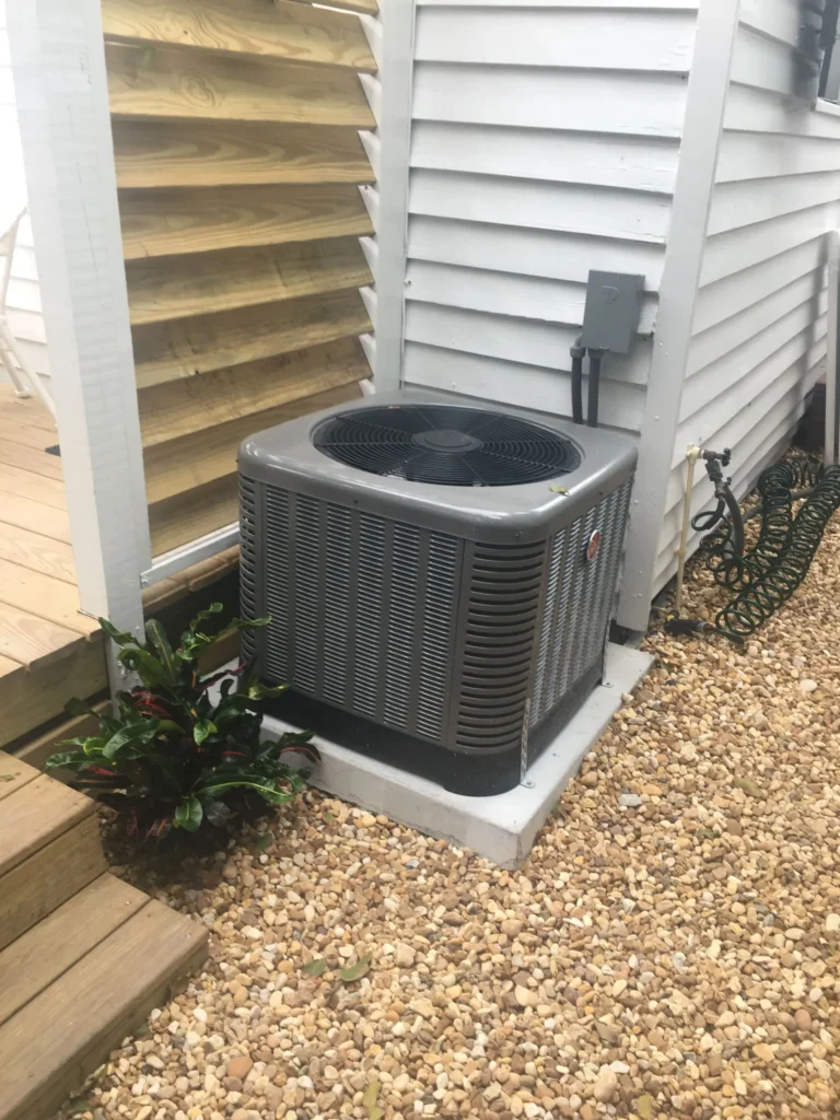 Rheem air conditioner condenser on a new concrete pad beside a backyard deck