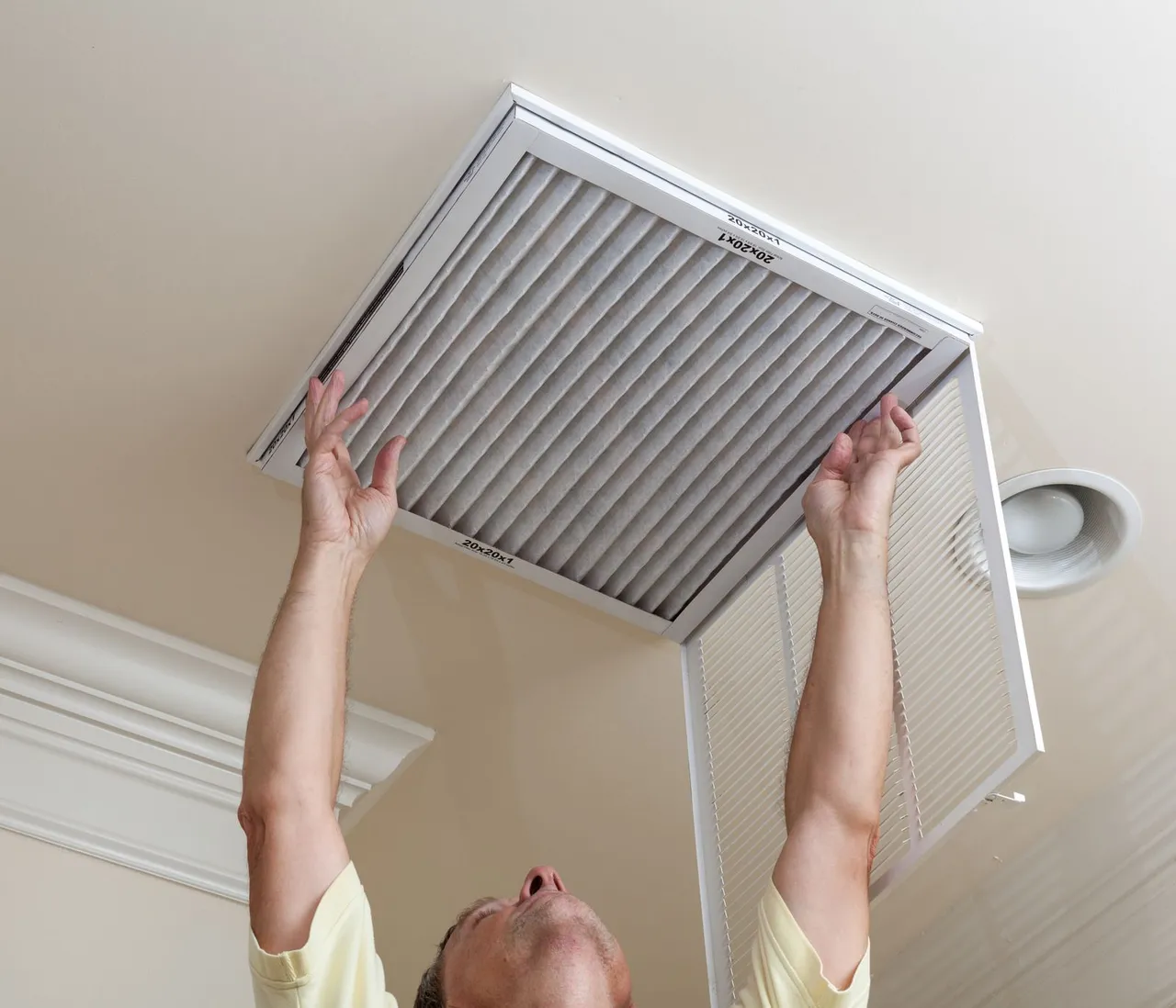Homeowner replacing a ceiling return-air filter